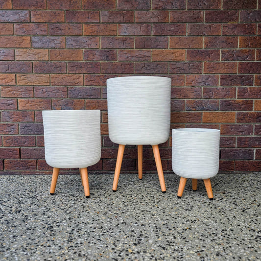 Set of three Sirroco Tripod Pots by Northcote Pottery with ribbed fibreclay design and timber legs against brick wall background